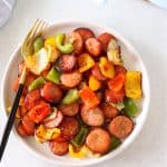Air fried sausage and peppers on a plate with fork.