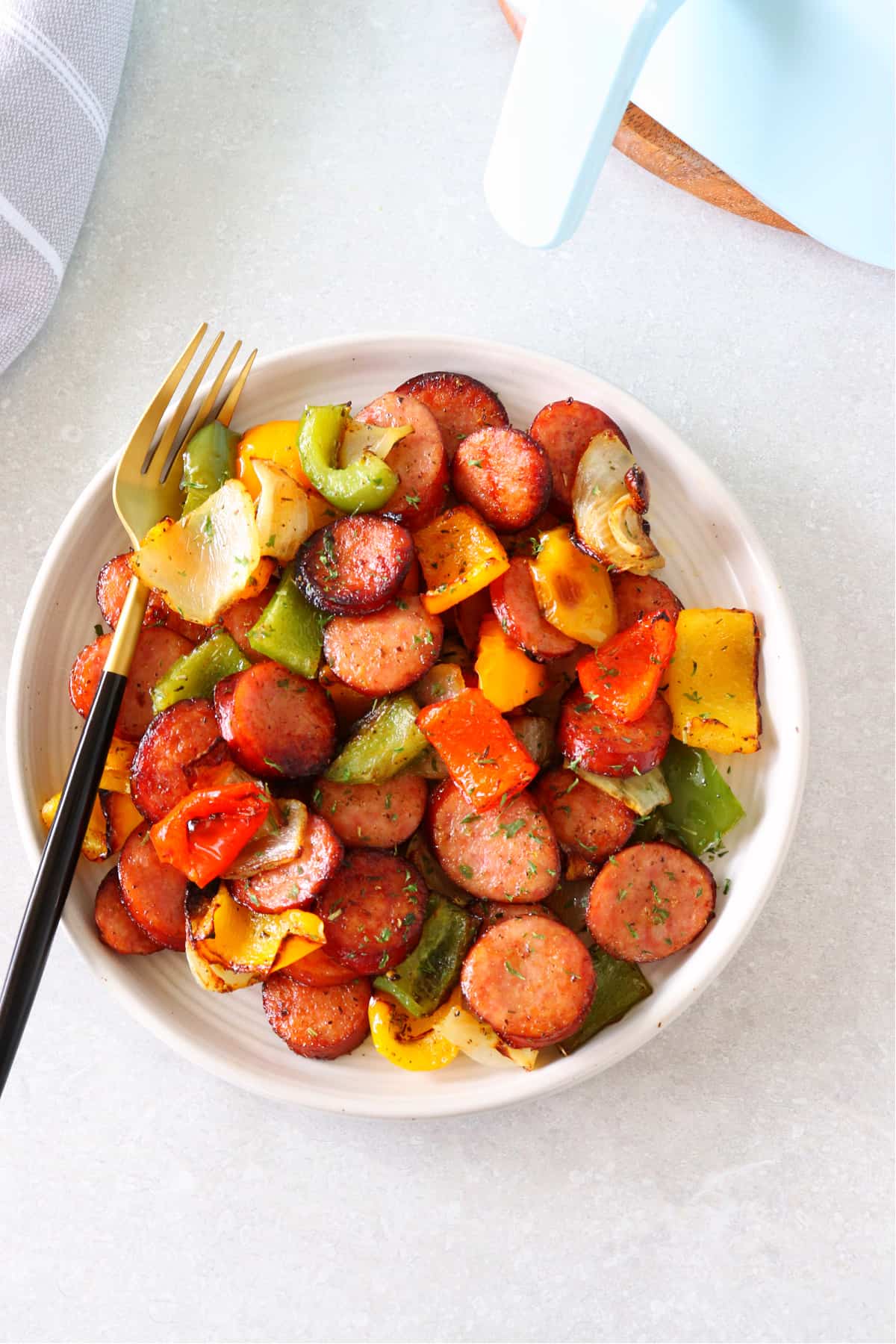 Air fried sausage and peppers on a plate with fork.