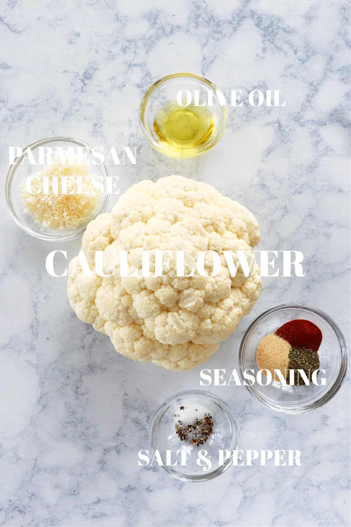 Head of cauliflower and other ingredients on a marble board.
