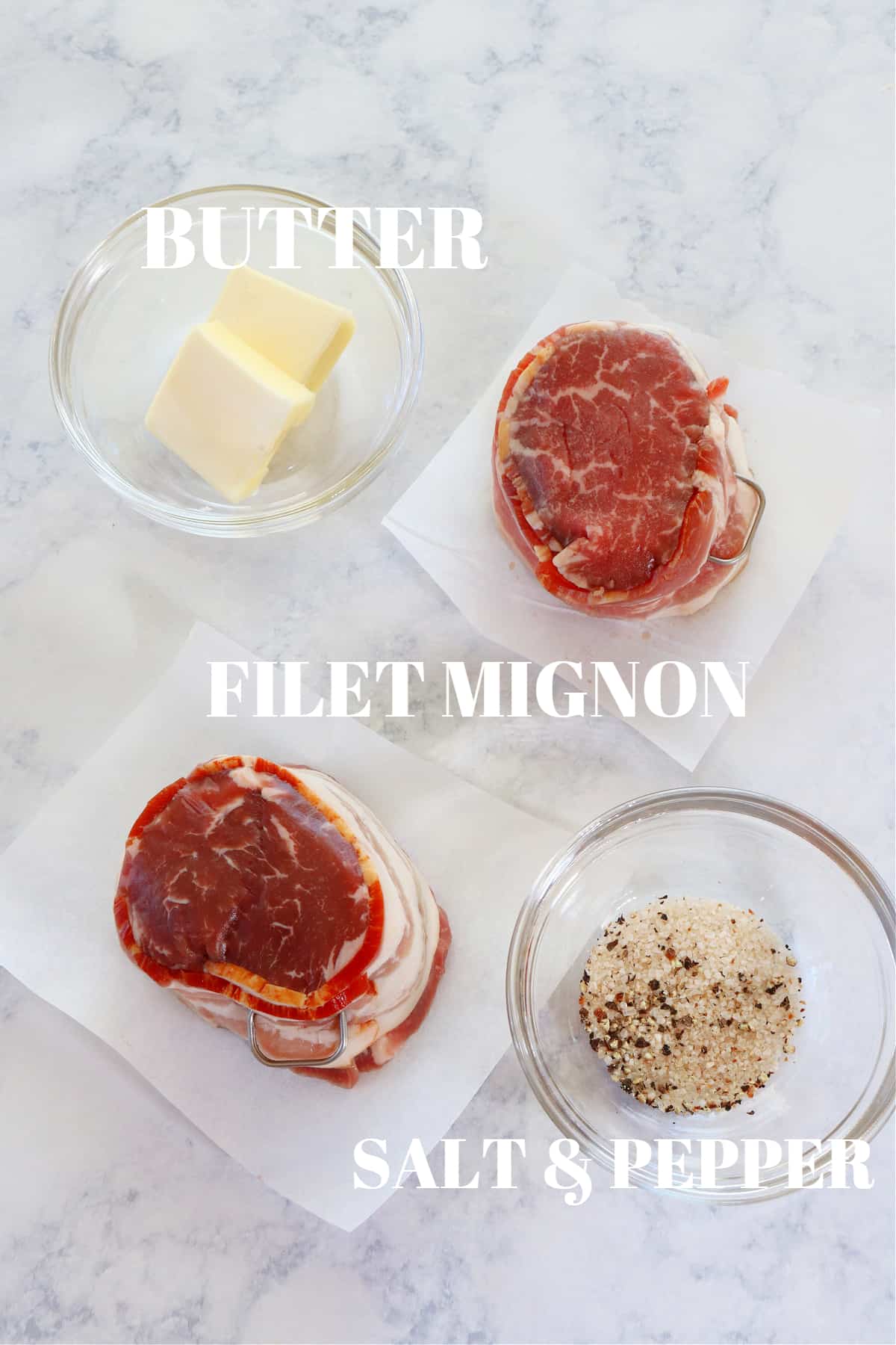 Filet mignon, butter and seasoning on a marble board.