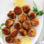 Meatballs with lemon slices on white oval plate.