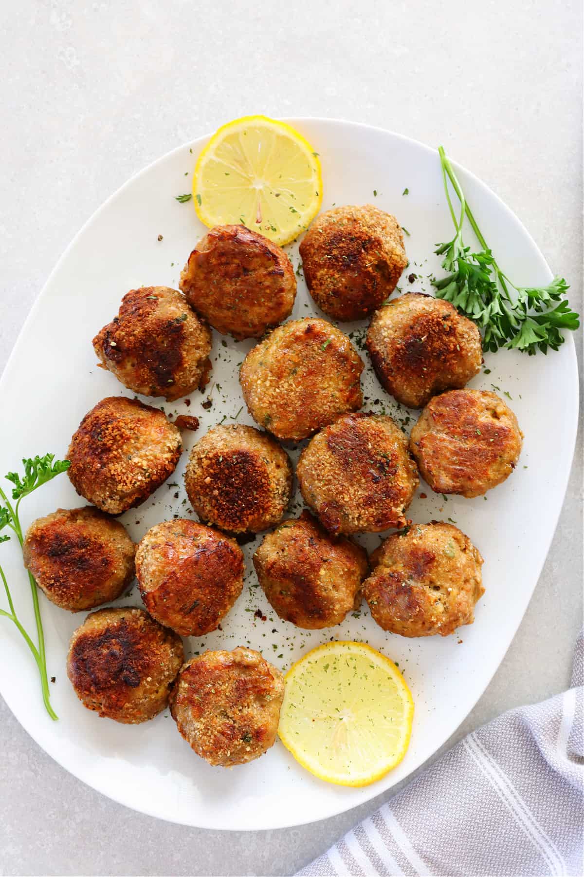 Meatballs with lemon slices on white oval plate.