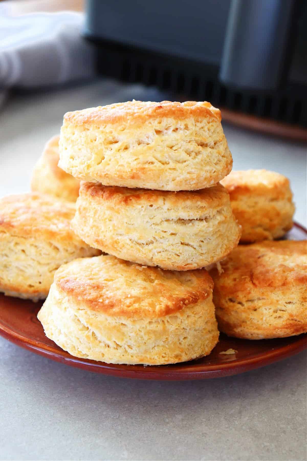 Air Fryer Biscuits Recipe Biscuits on a plate next to air fryer.