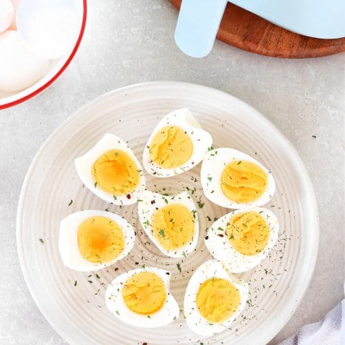 Hard boiled eggs on a plate next to the air fryer.