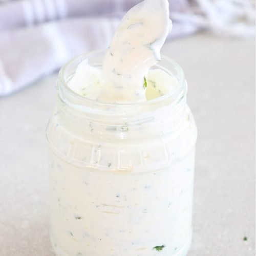 Ranch dressing in a glass jar with spoon.