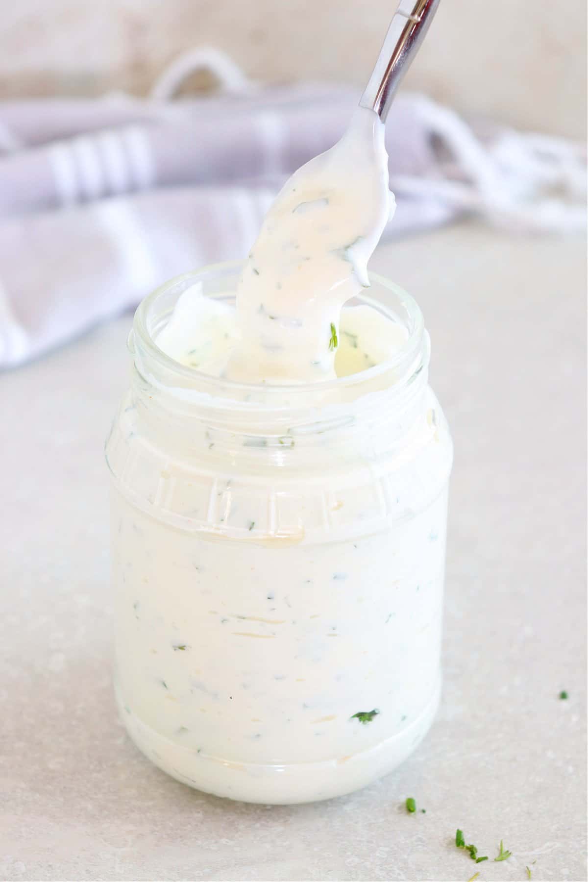 Ranch dressing in a glass jar with spoon.