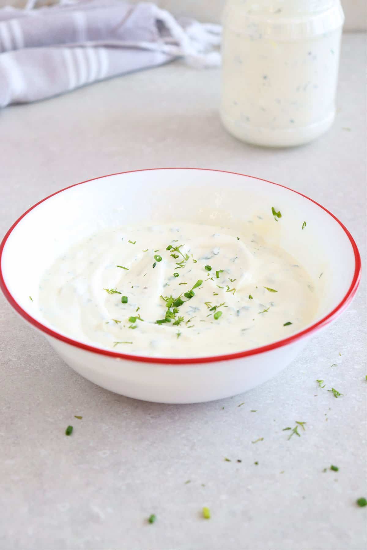 Ranch dip in a bowl with red rim.