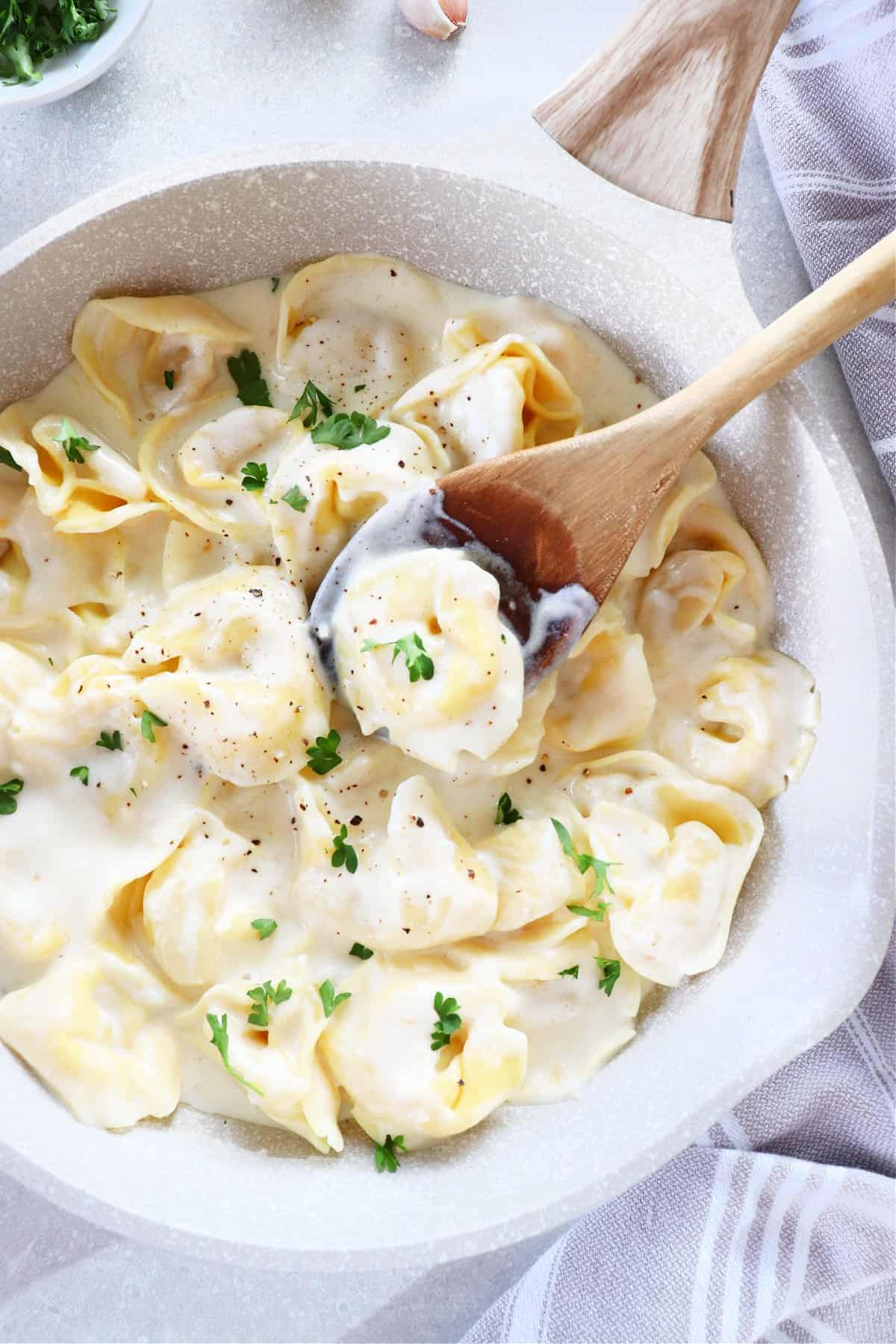 Tortellini in Alfredo sauce in a pan.