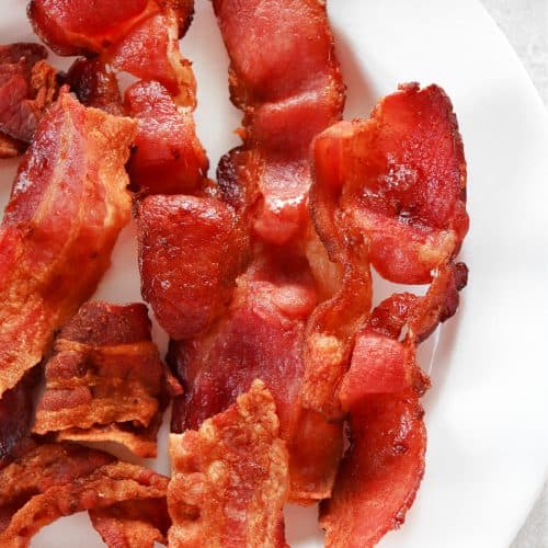 Cooked bacon on white plate.