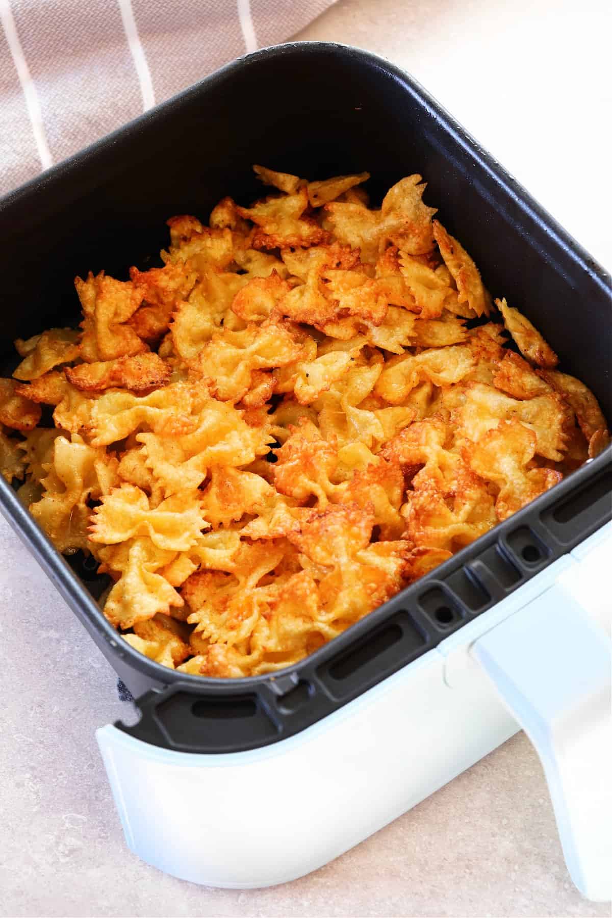 Fried pasta in air fryer basket.