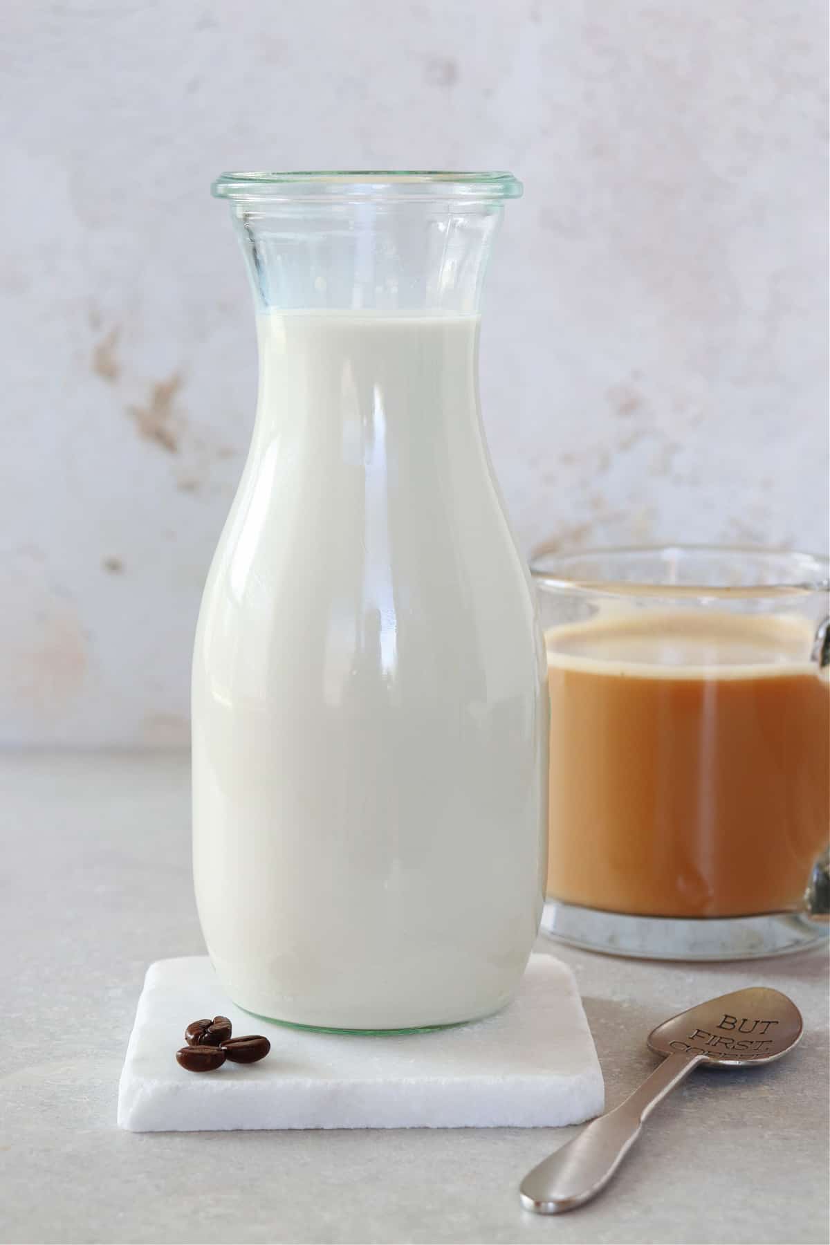 Creamer in a carafe next to coffee in a mug.