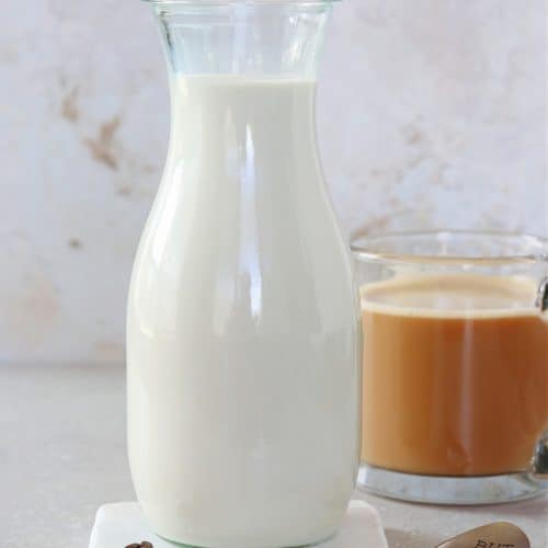 Creamer in a carafe on a marble coaster.