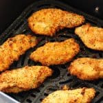 Chicken tenders in an air fryer basket.