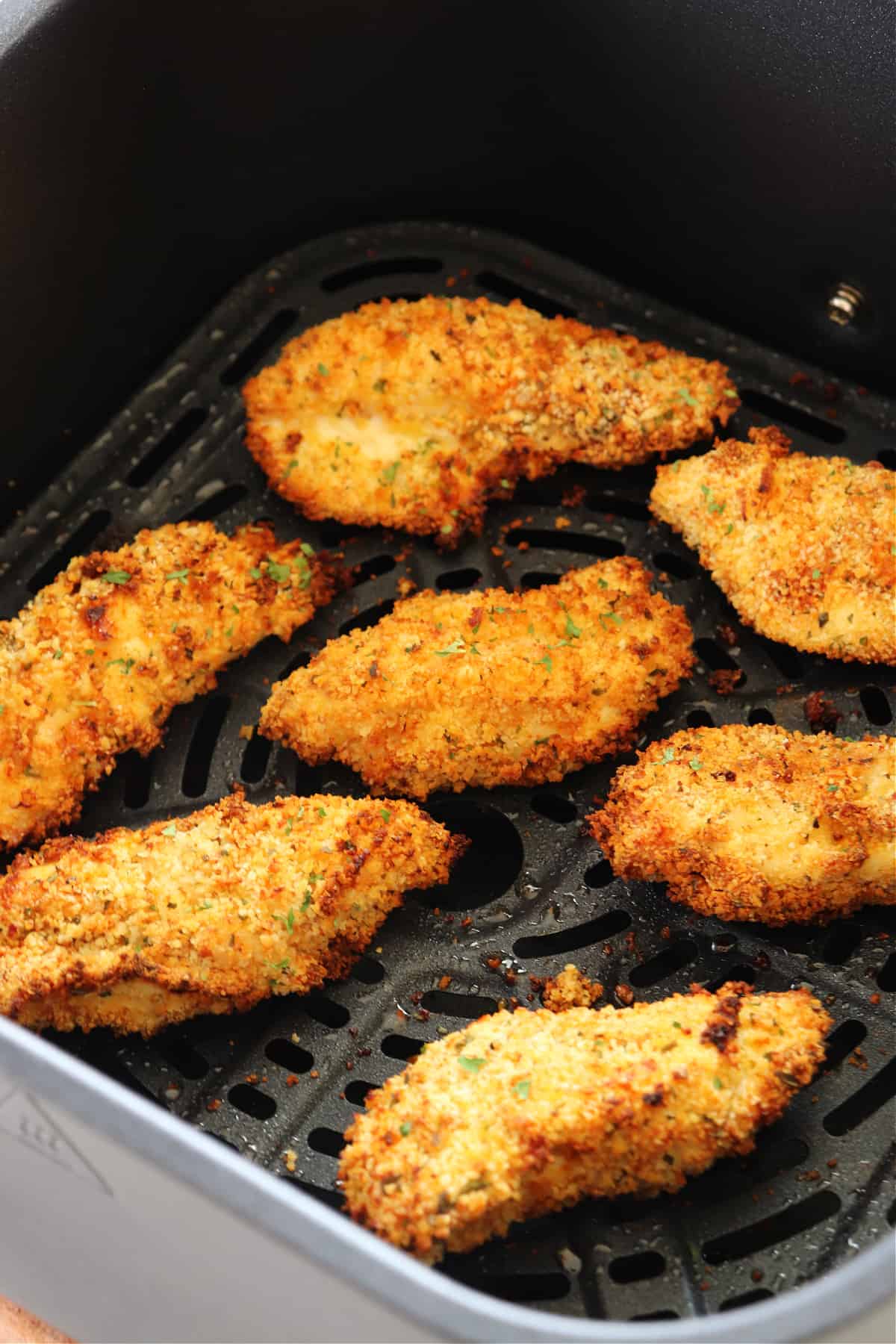 Chicken tenders in an air fryer basket.