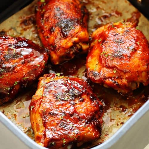 Chicken thighs with BBQ sauce in the air fryer basket.