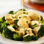 Cheddar cheese sauce drizzled over cooked broccoli in a bowl.