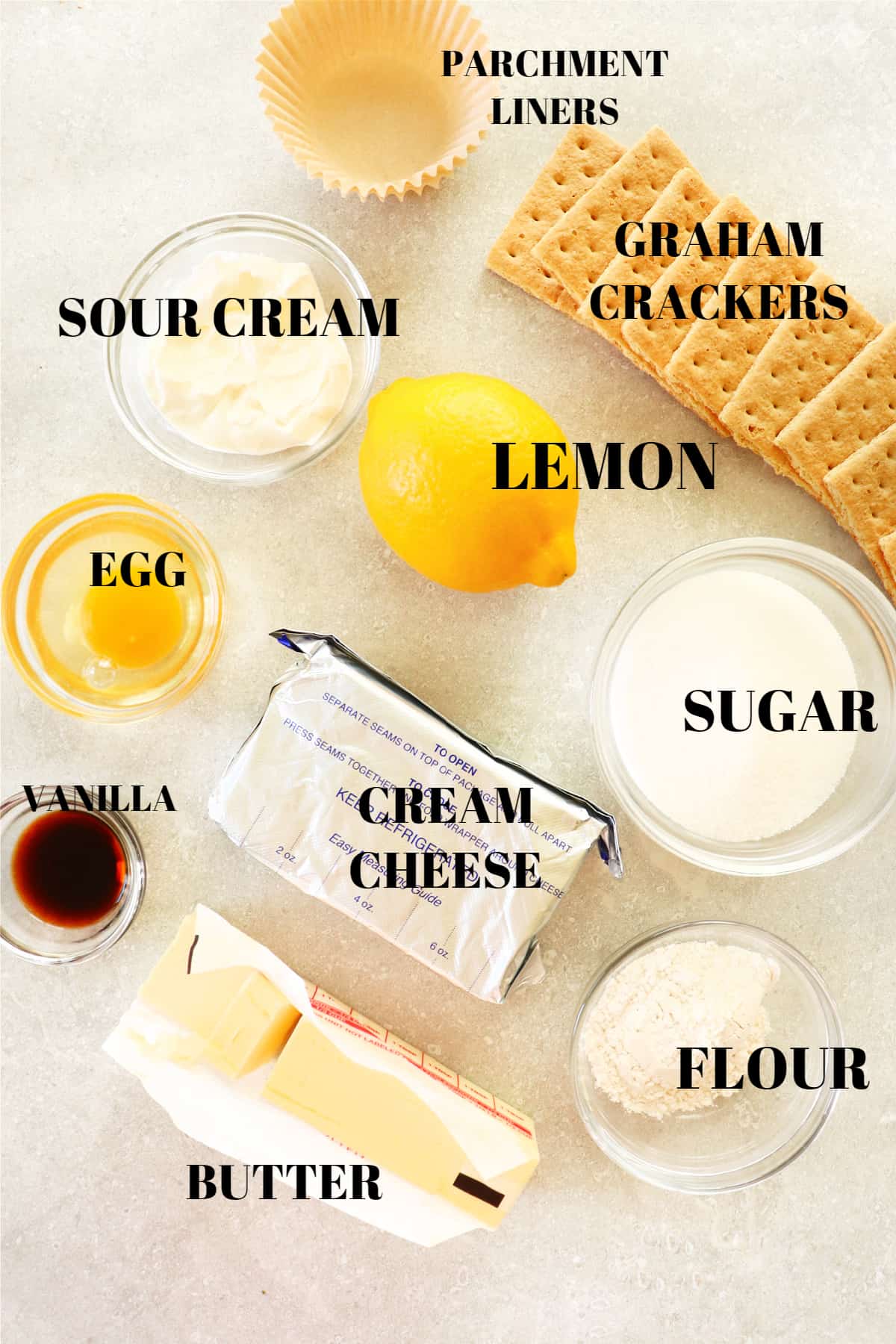 Ingredients for mini lemon cheesecakes on a gray board.