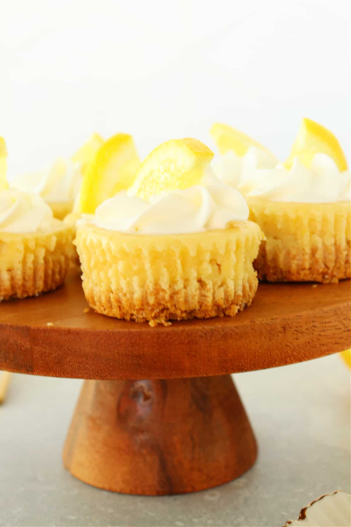 Mini cheesecakes on a wooden cake stand.