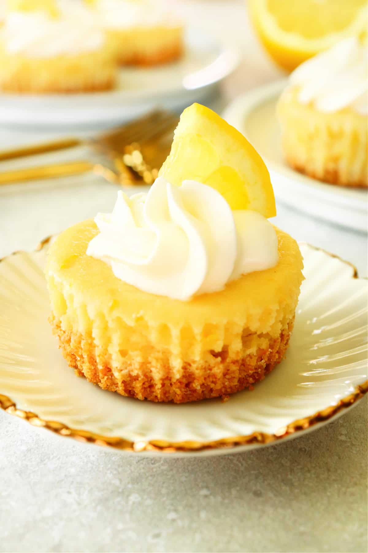 Lemon mini cheesecake on a white plate with gold rim.