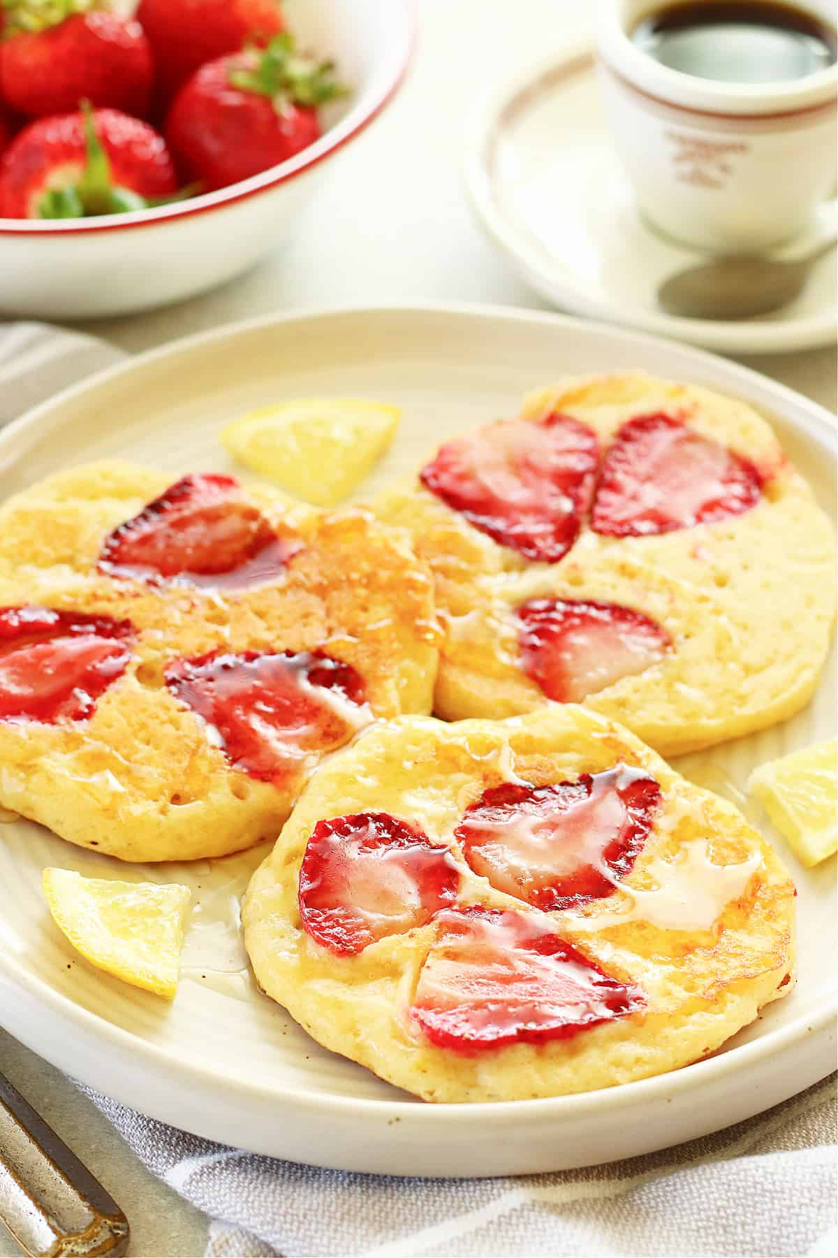 Three strawberry pancakes on a plate.