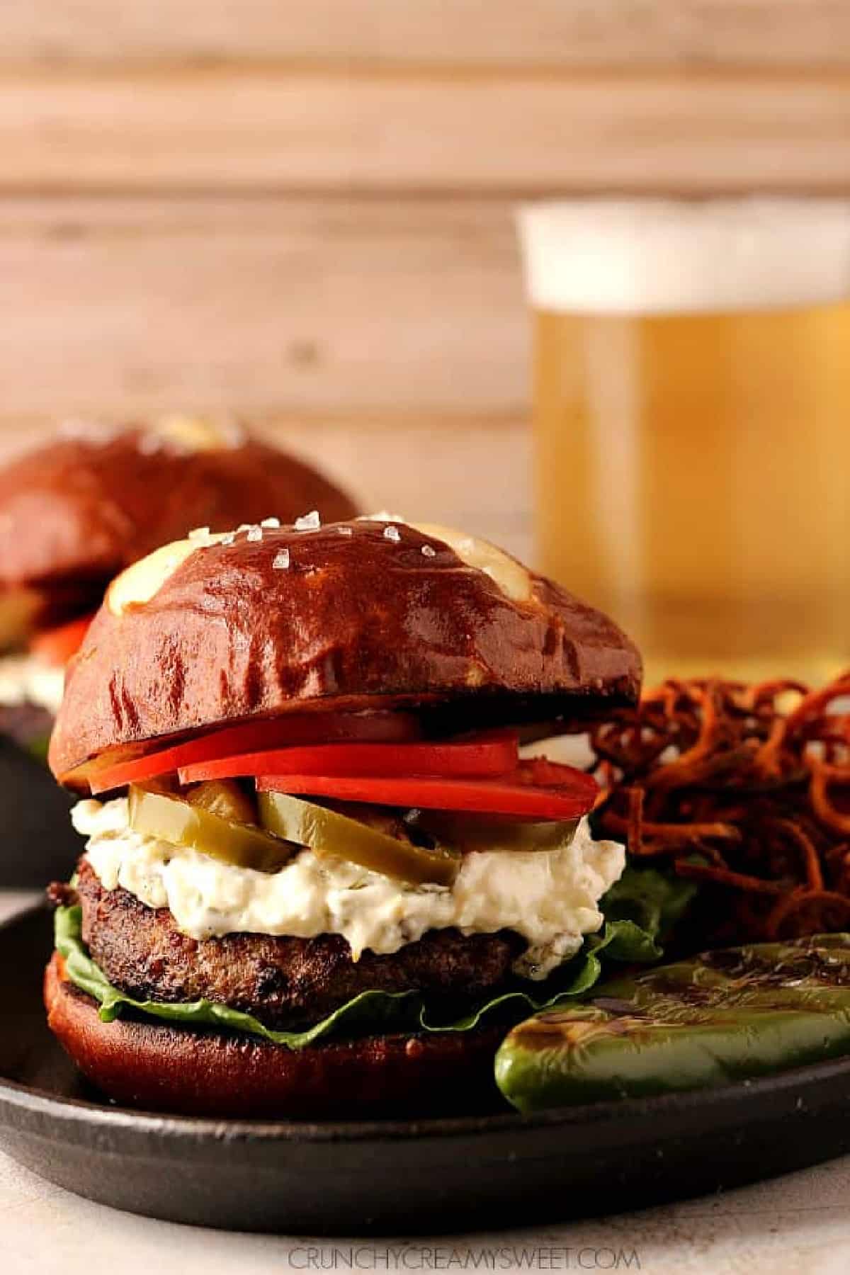 Burger with pretzel bun on a black cast iron skillet.