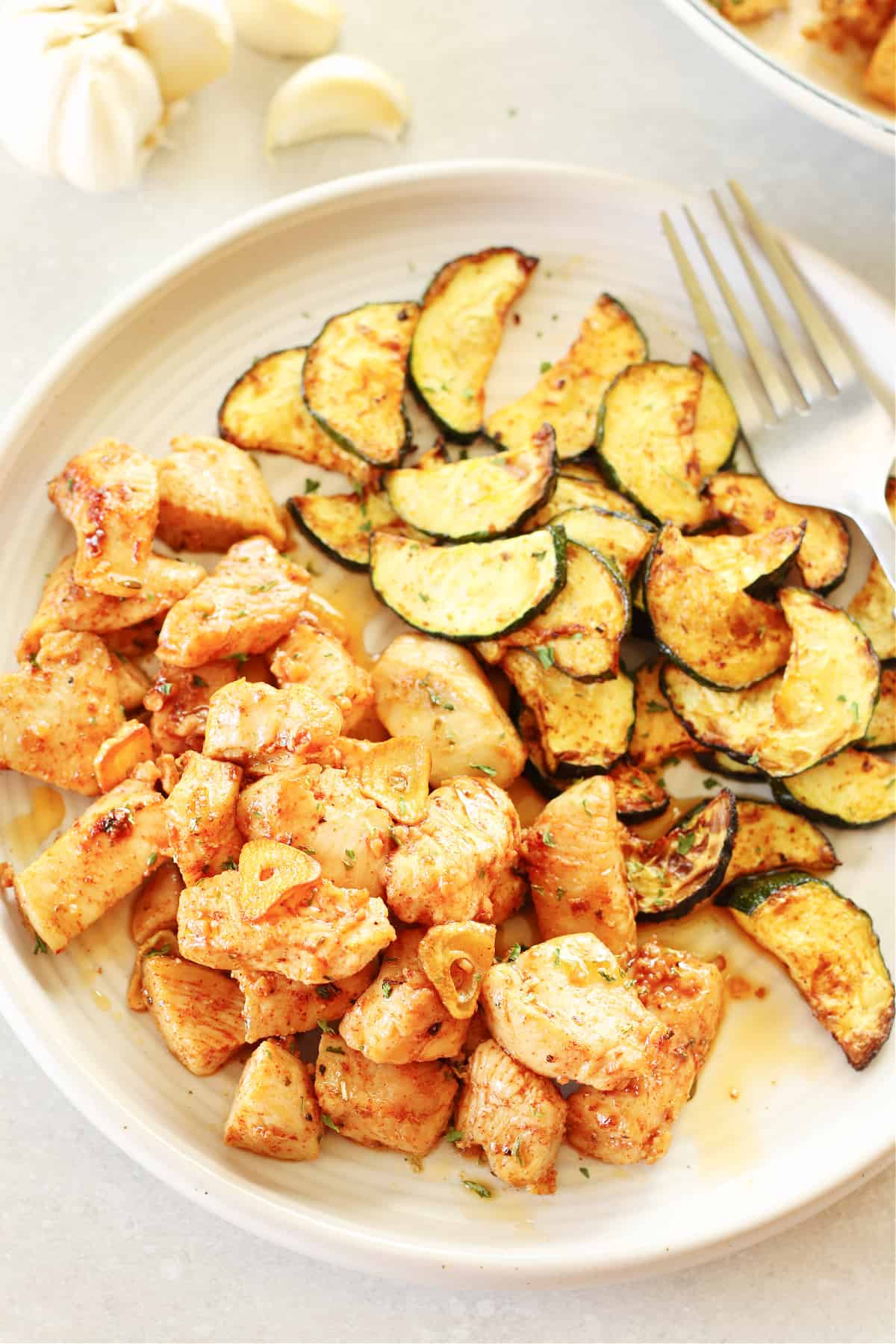 Chicken bites and cooked zucchini slices on a dinner plate.