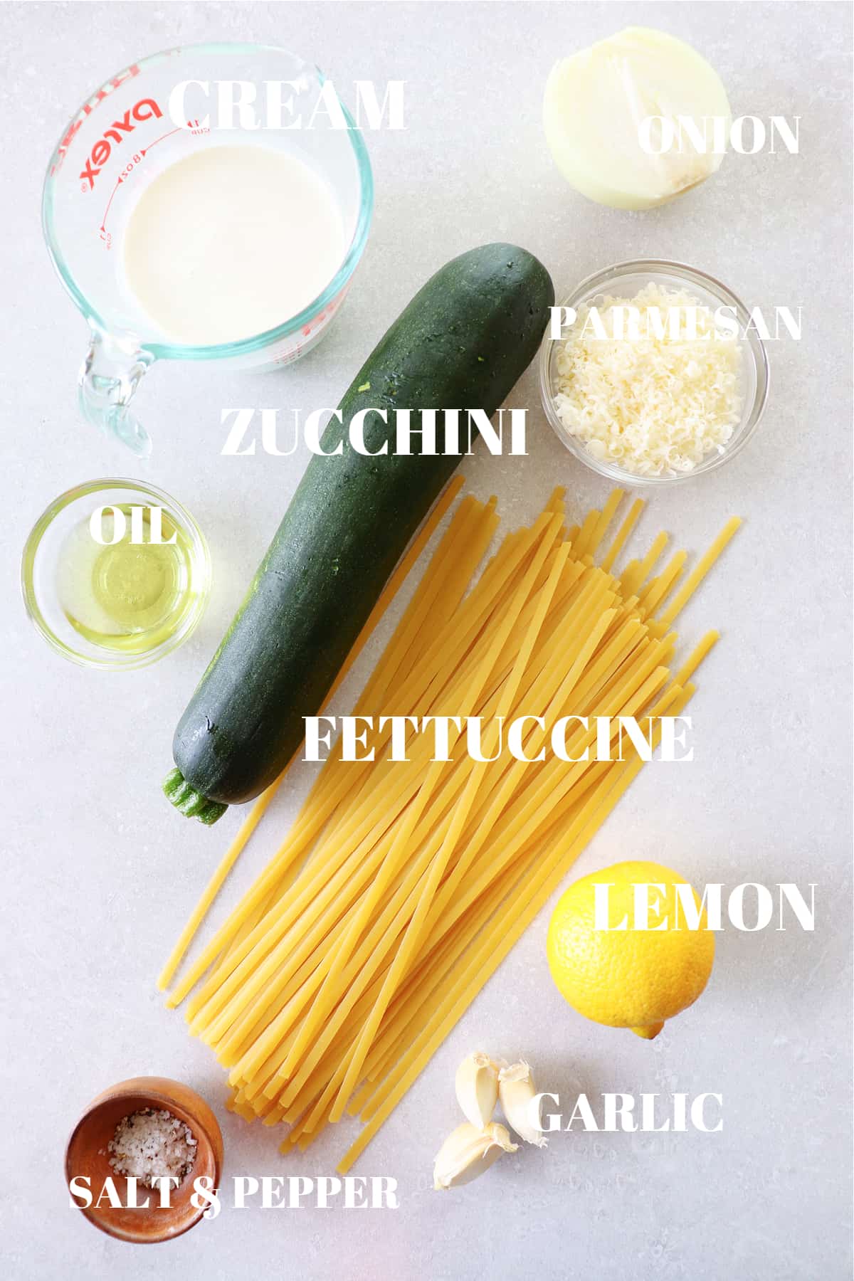 All ingredients for zucchini pasta dish on a gray board.
