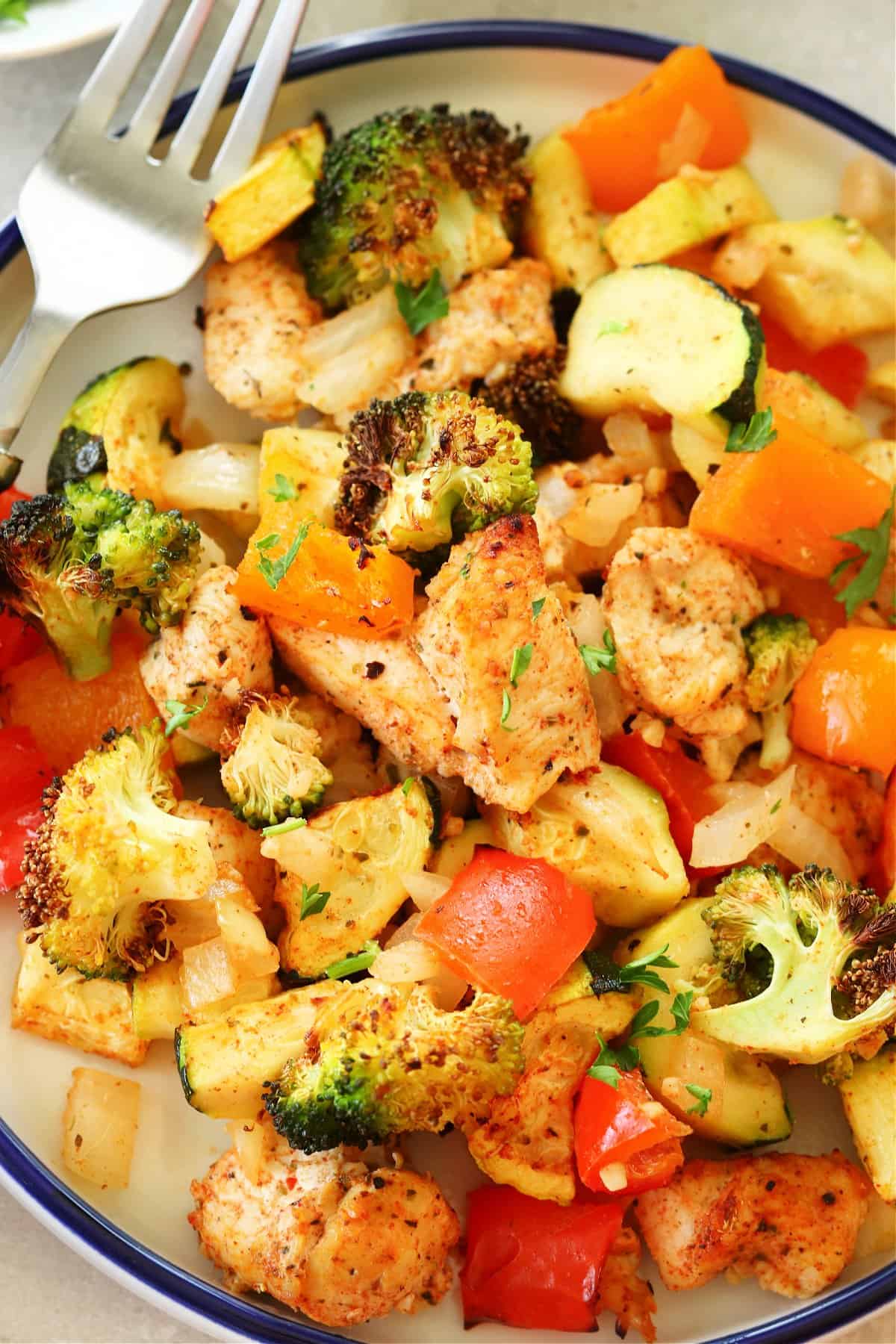 Chicken and vegetables on a white plate with blue rim.