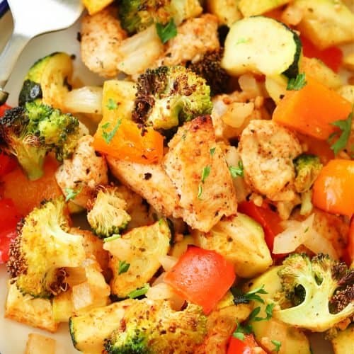 Close up of cooked chicken pieces and chopped vegetables.