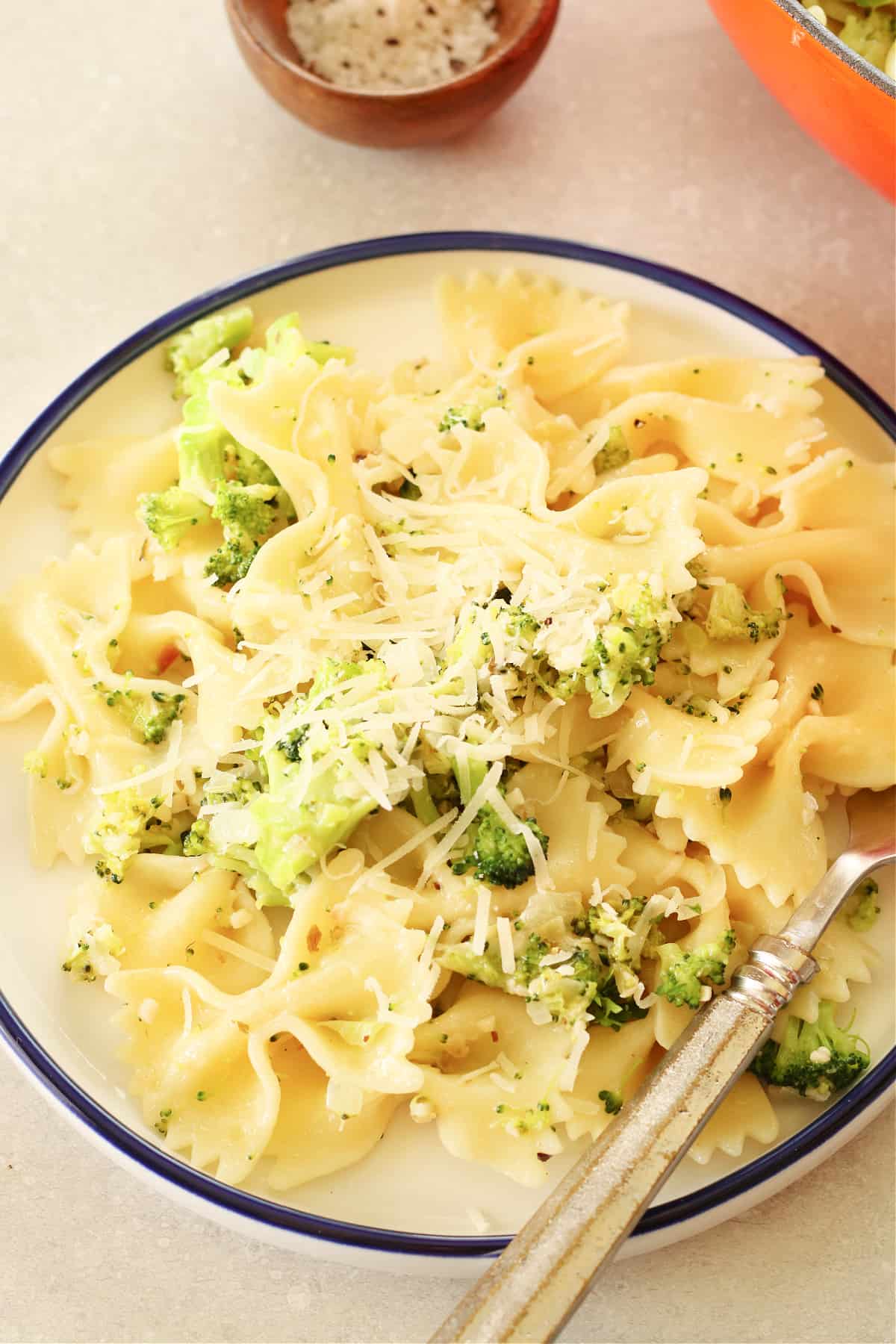 Bow tie pasta and broccoli on a plate with blue rim.