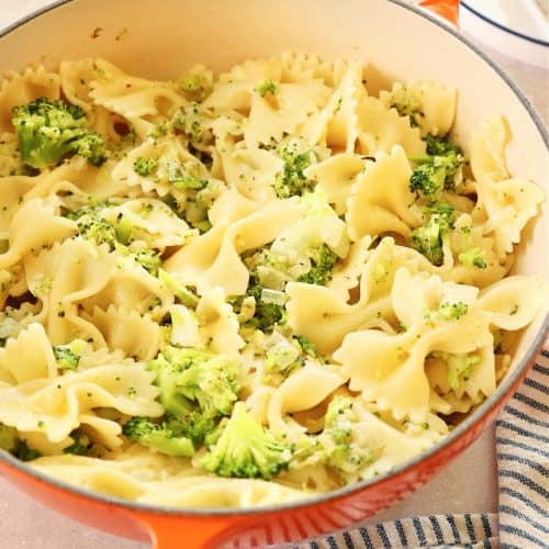 Pasta with broccoli in an orange pan.