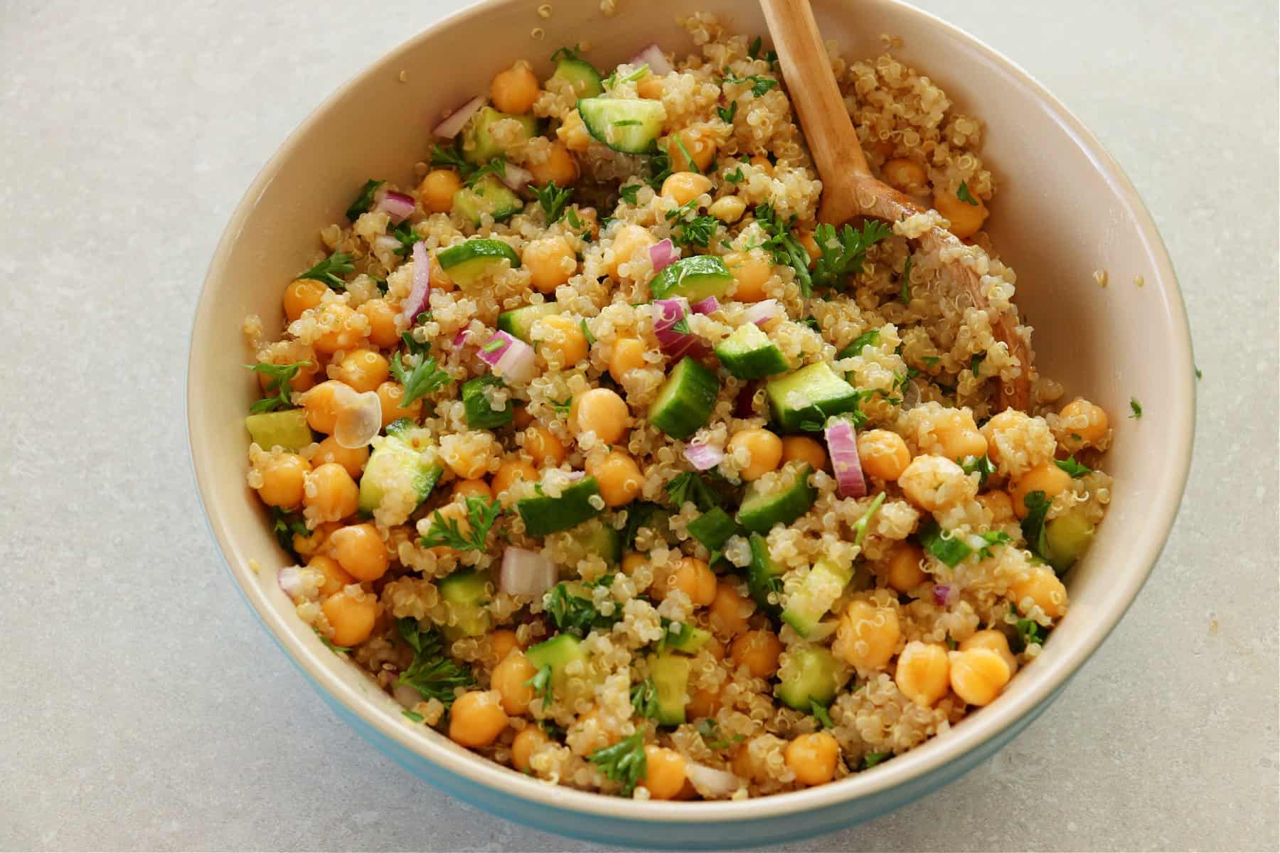 Salad with quinoa, chickpeas and cucumber in a mxing bowl.