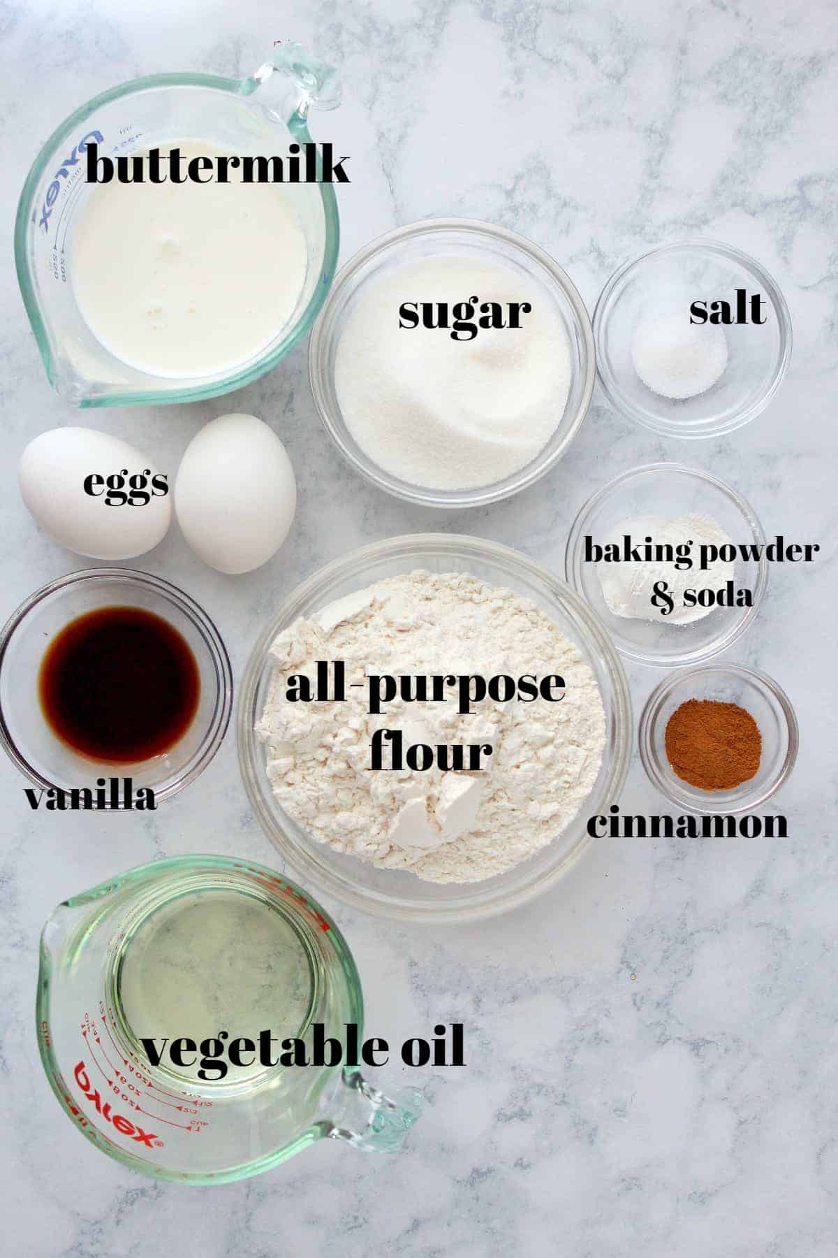Ingredients for crumb cake in glass bowls and cups, on a marble board.