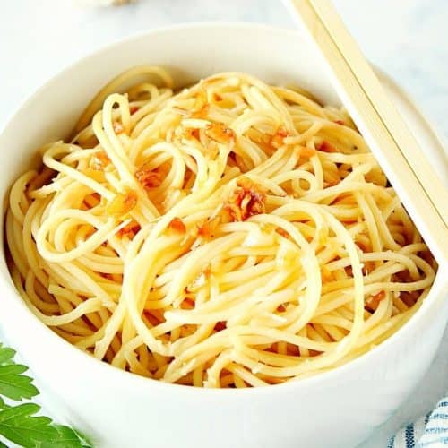 Close up shot of noodles with garlic in a bowl. Chopsticks are placed on the edge.