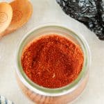 Close up photo of chili seasoning in a glass jar, on a gray board.