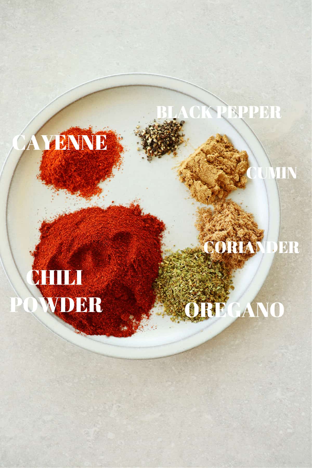 Chili, cayenne, black pepper, cumin, coriander and oregano in little mounds on a small plate.