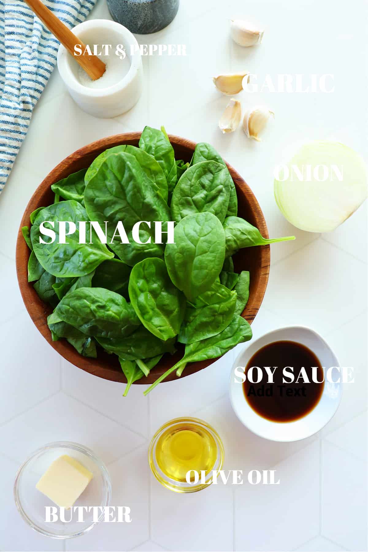 Fresh spinach, onion, garlic cloves, butter, olive oil and salt in bowls on a white board.