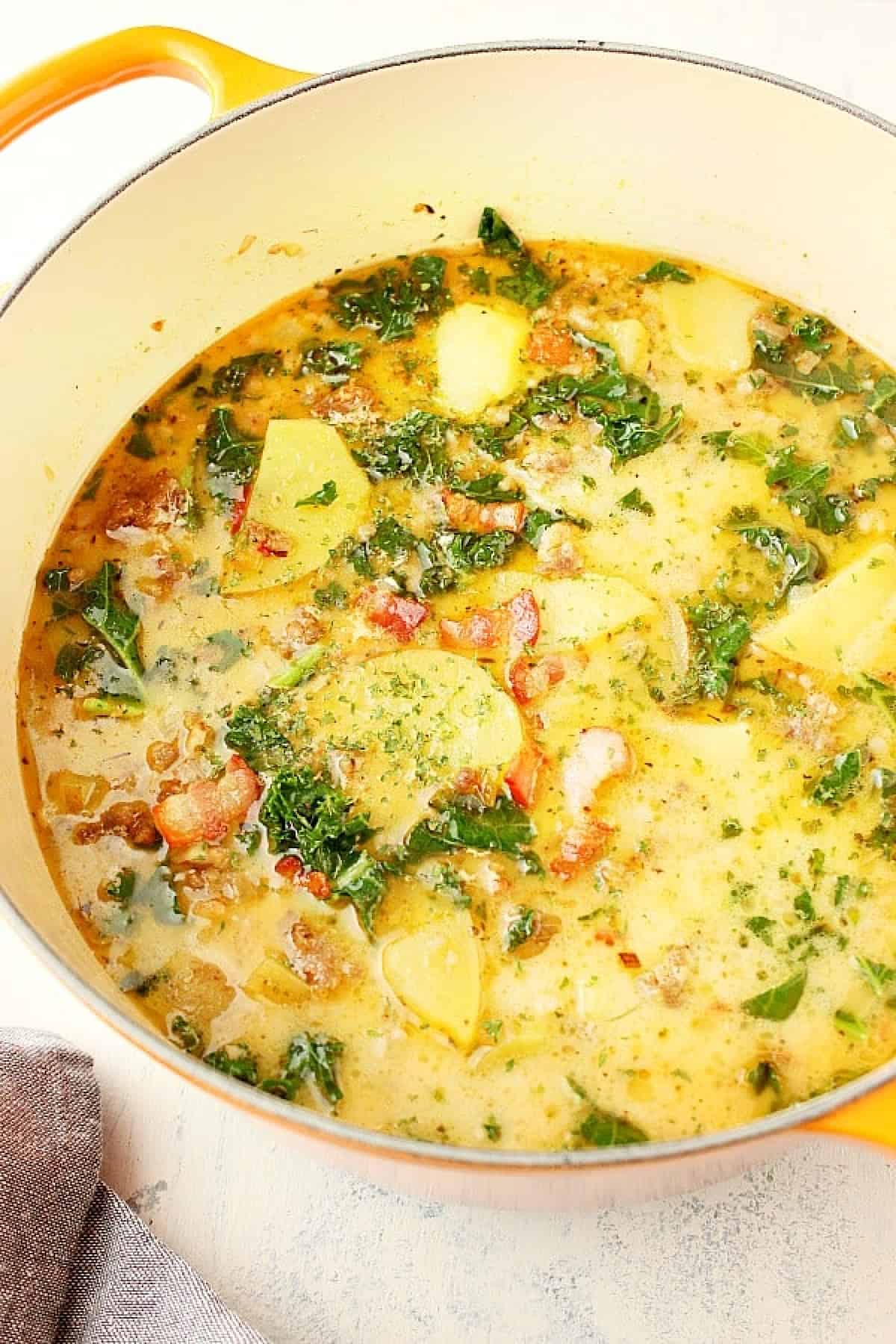 Zuppa Toscana in a yellow Dutch oven on a white board.