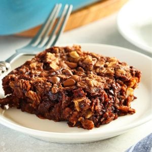 Square image of a square serving of chocolate oatmeal on a white plate with fork.