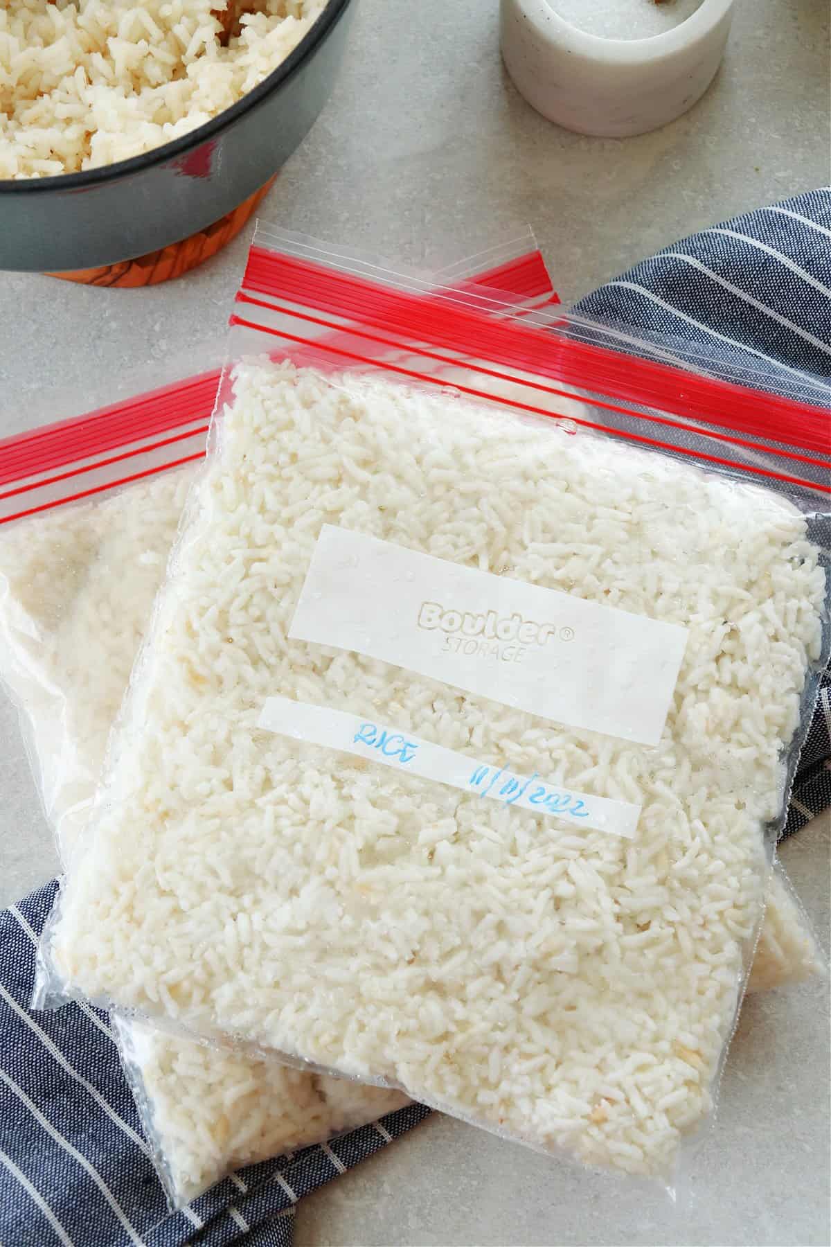 Cooked rice in two freezer bags on a gray board.