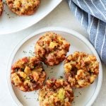 Four stuffing muffins on a plate with kitchen towel next to it.