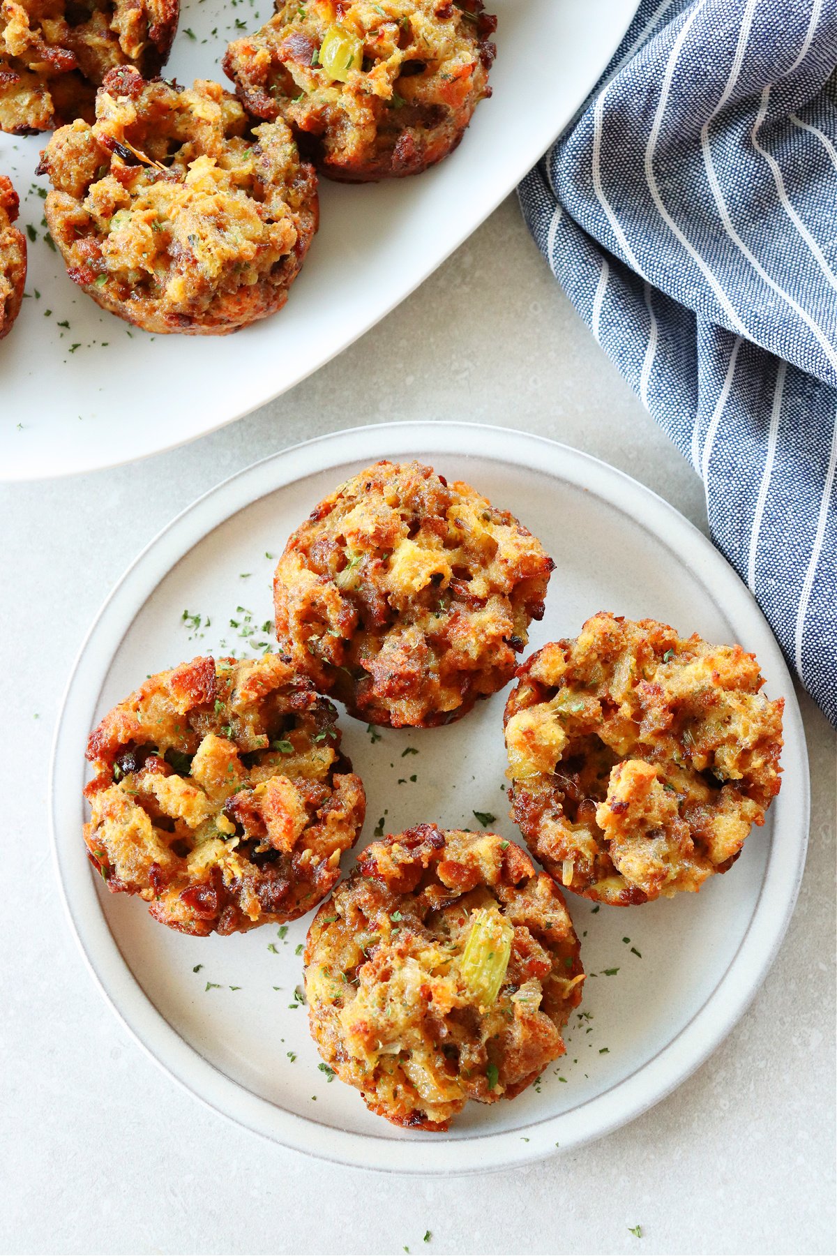 Four stuffing muffins on a plate with kitchen towel next to it.