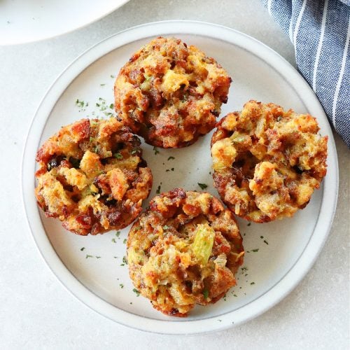 Square image of four muffins made with stuffing on a gray plate.