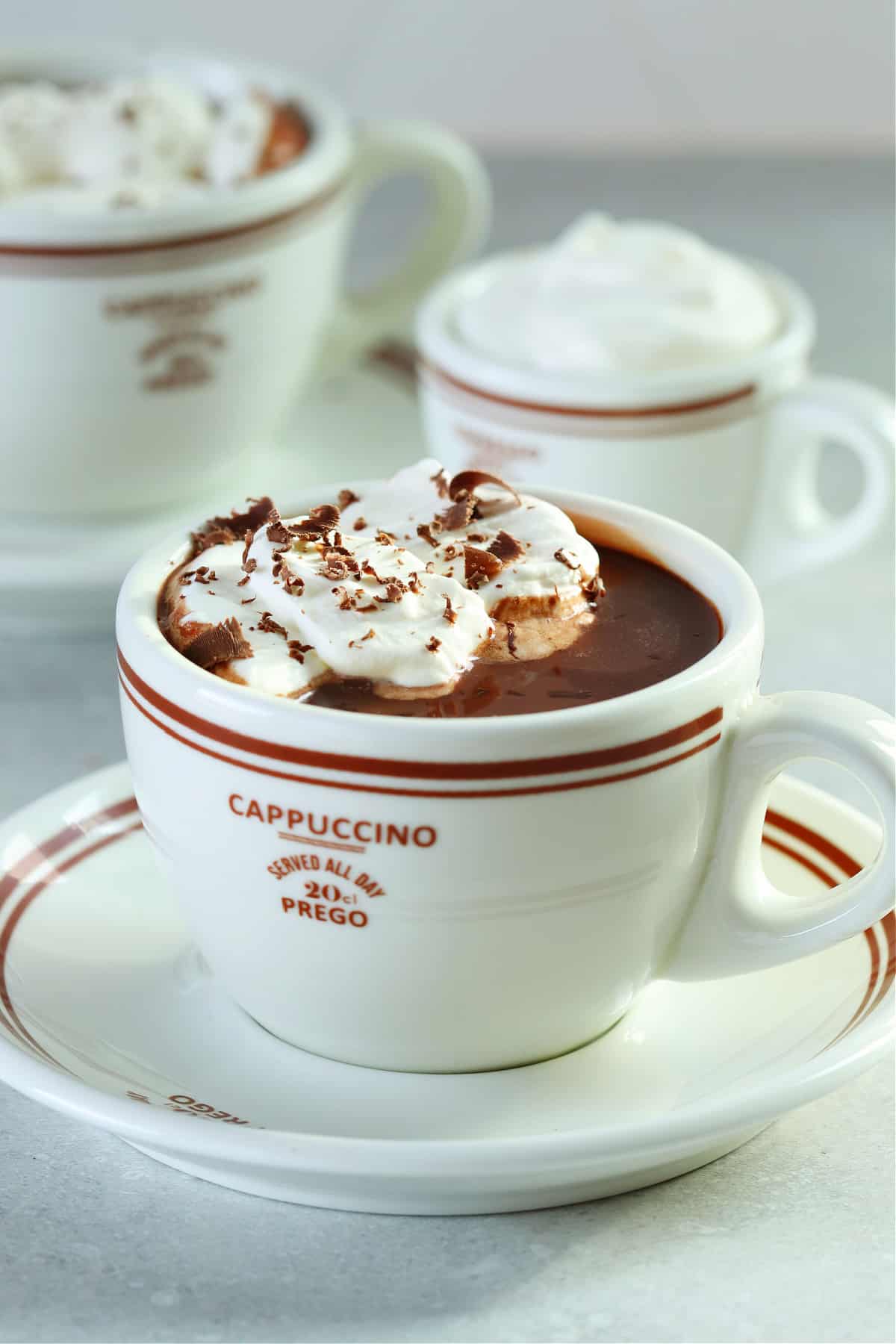 Hot chocolate in a mug on a saucer on a gray background.