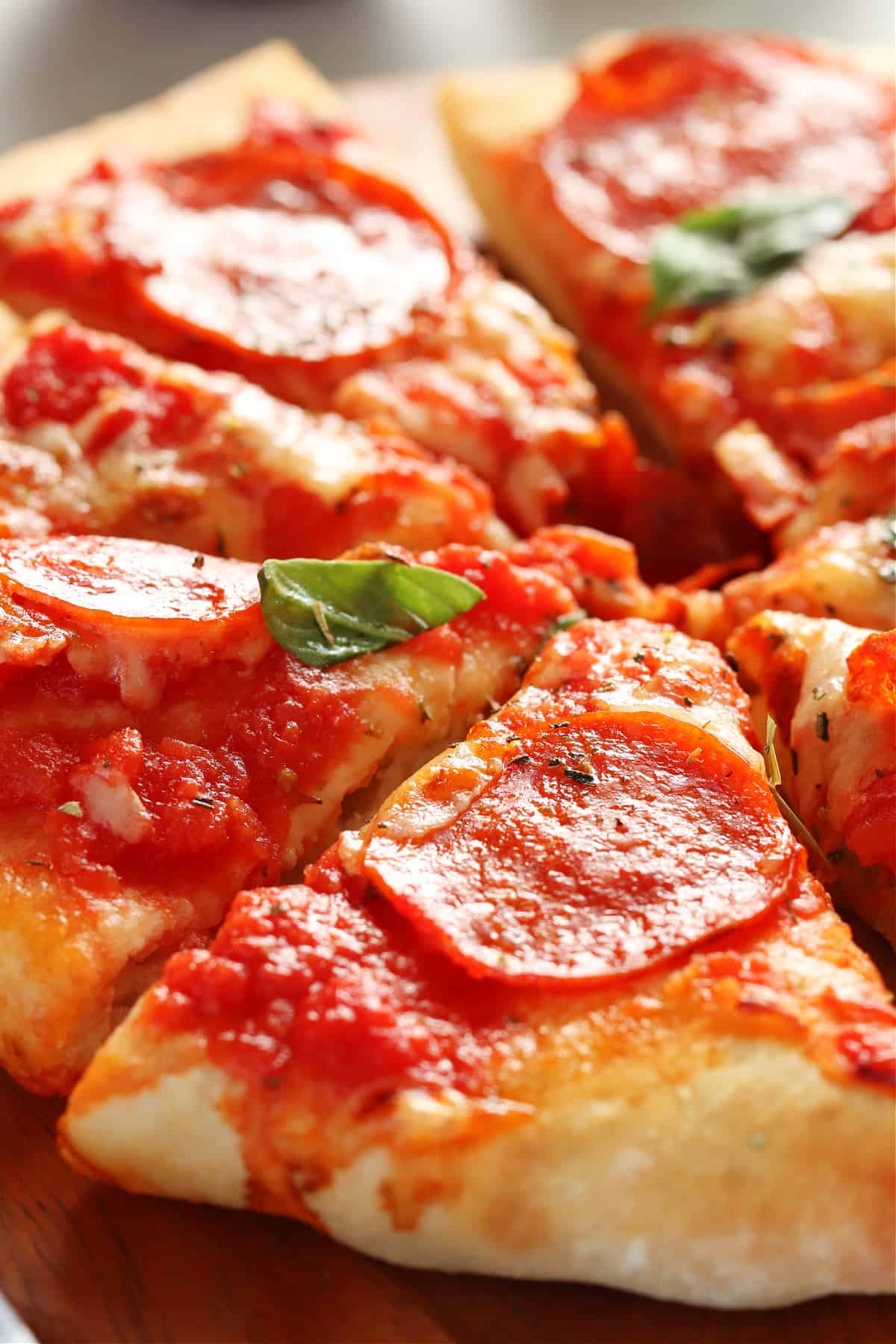 Close up on a slice of pizza with pepperoni on a wooden board.