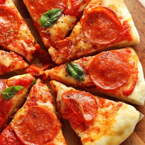 Square image of sliced pizza with cheese and pepperoni on a wooden board.