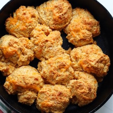 Biscuits in a black cast iron skillet on a white board.