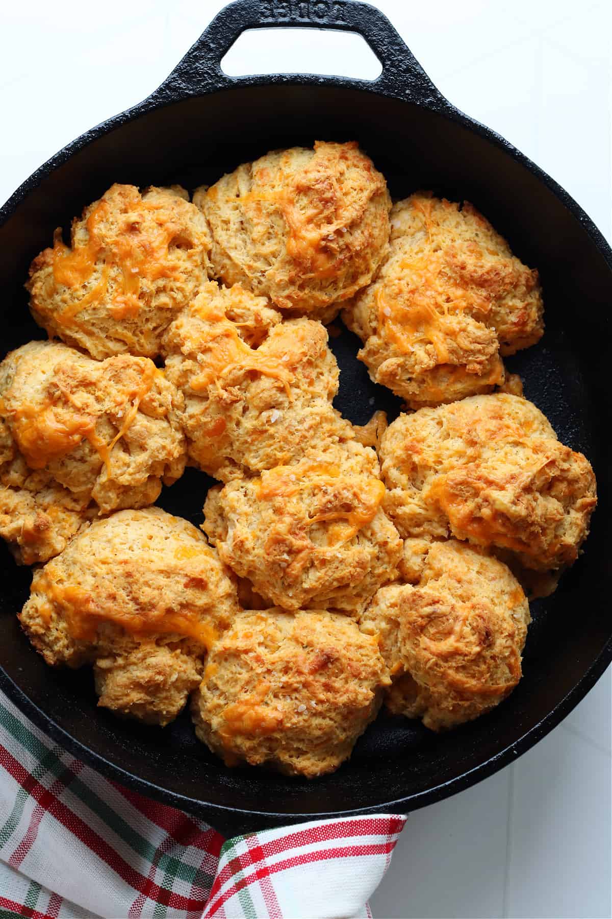 Biscuits in a black cast iron skillet on a white board.
