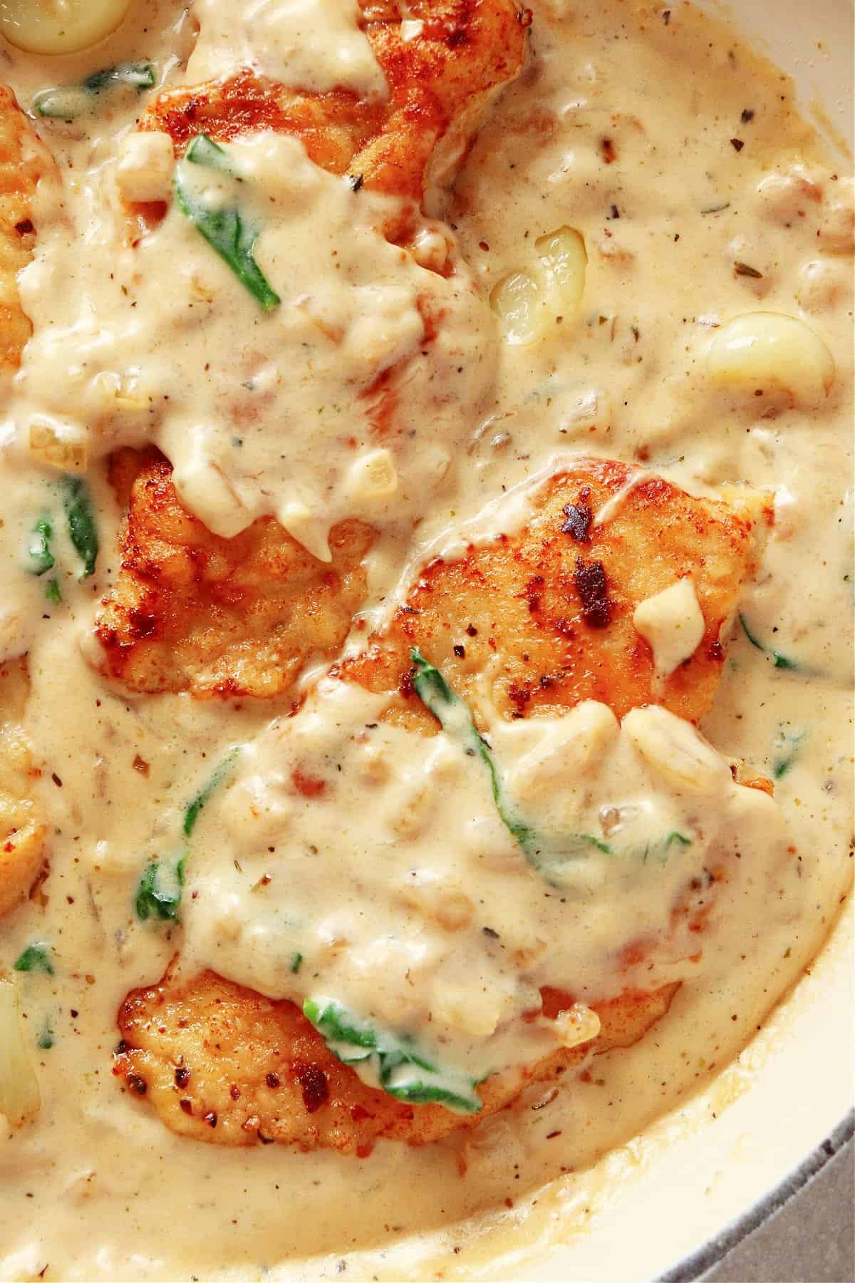 Three chicken breasts in creamy sauce with garlic and spinach.
