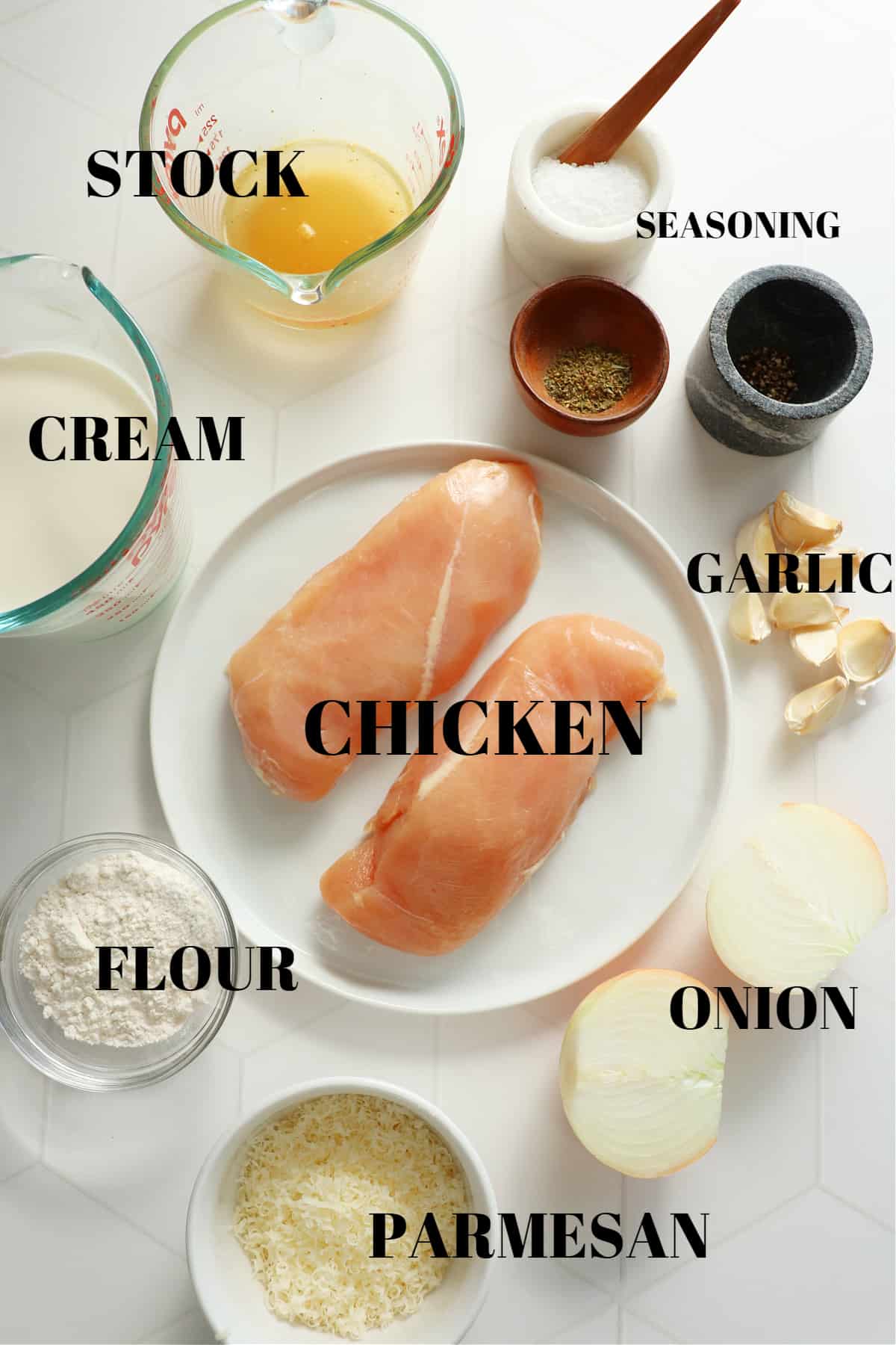 Ingredients for creamy garlic chicken dish on a white tile board.